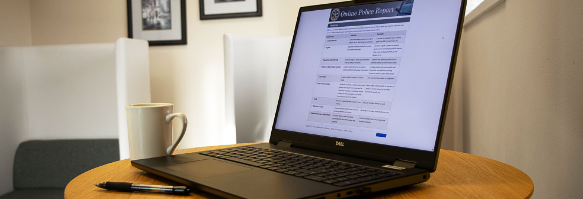 Computer laptop sitting on a round table with the screen showing the Online Police Report form.