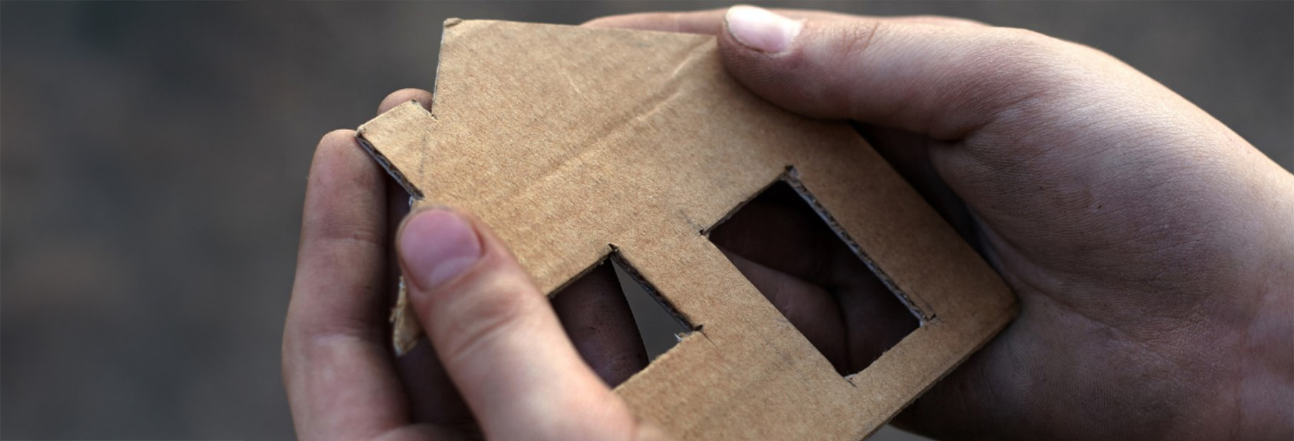 Hands holding a cardboard cutout of a house